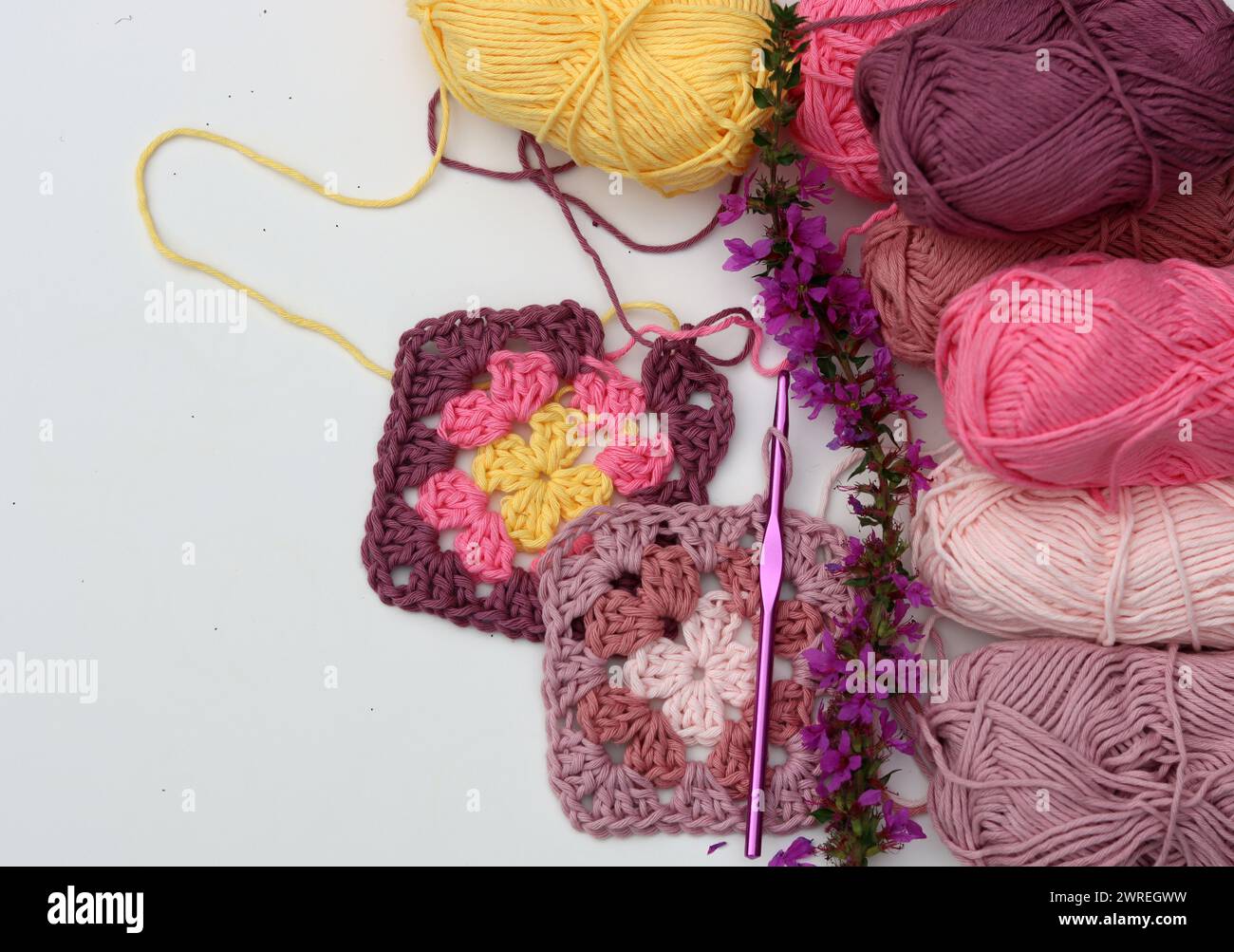 Motif au crochet, fleurs, boules de fil de coton vue de dessus photo. Carré Granny en fil organique rose doux. Motif crochet fait à la main sur fond blanc Banque D'Images