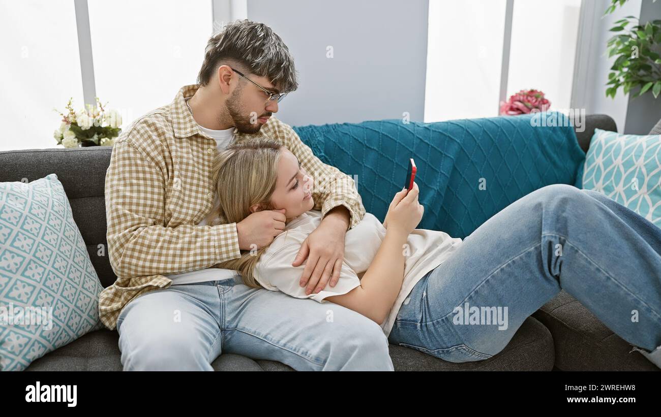 Un couple aimant profite de temps de qualité sur un canapé confortable dans un salon confortable, véhiculant intimité et détente. Banque D'Images