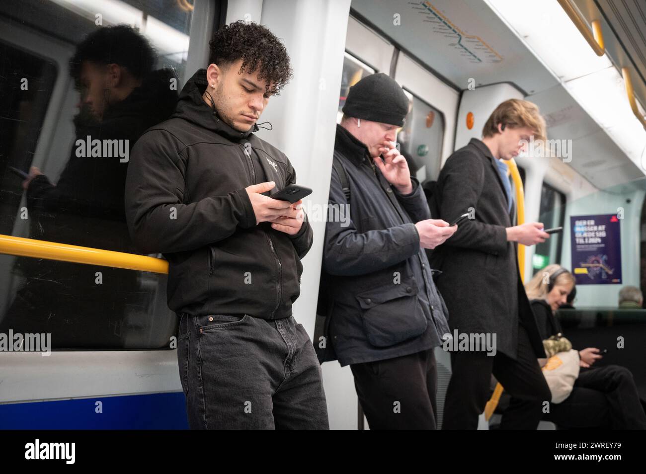 Voyageurs utilisant un téléphone portable dans le métro de Copenhague Banque D'Images