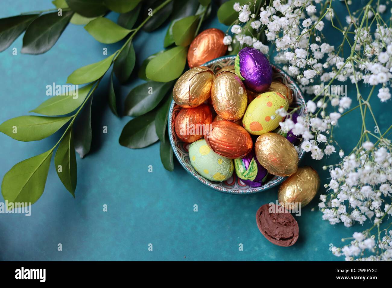Couleurs vibrantes de bonbons de Pâques. Nature morte colorée avec des fleurs blanches de gypsophila et des œufs en chocolat. Banque D'Images