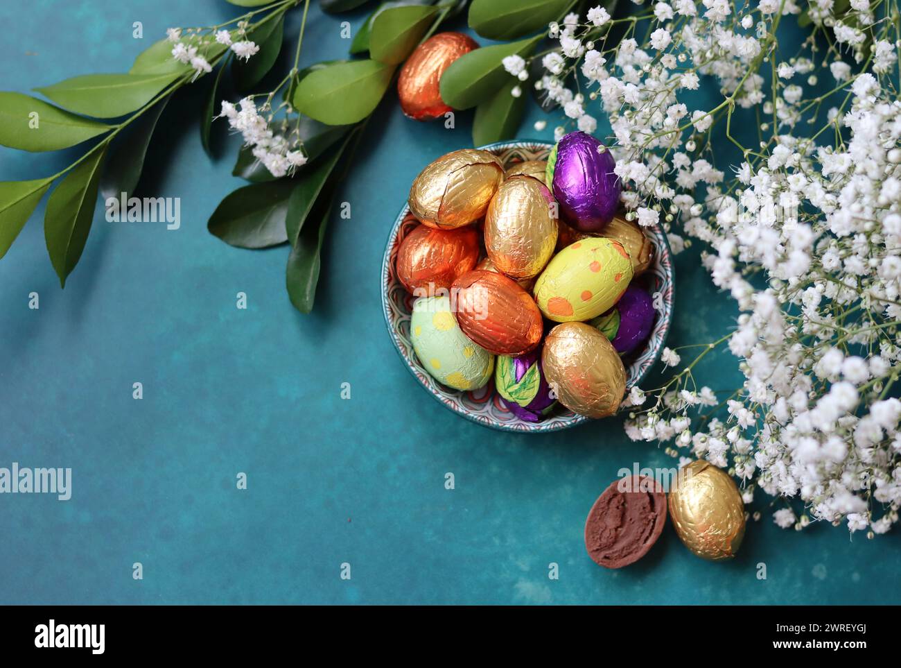Couleurs vibrantes de bonbons de Pâques. Nature morte colorée avec des fleurs blanches de gypsophila et des œufs en chocolat. Banque D'Images