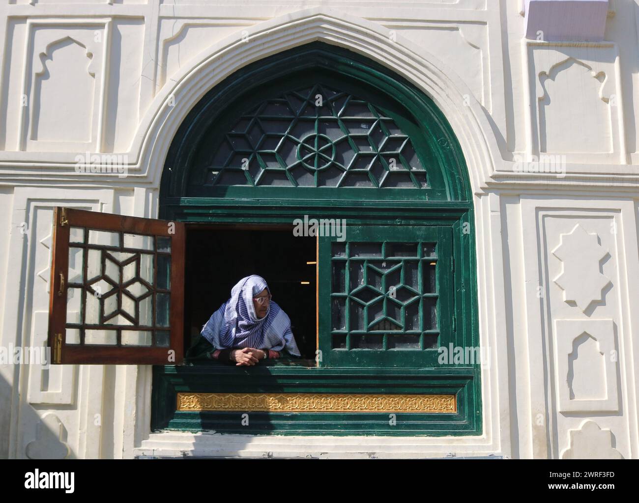Srinagar, Inde. 12 mars 2024. 12 mars 2024, Srinagar Cachemire, Inde : Une femme regarde par la fenêtre d'une mosquée le premier jour du Ramadan à Srinagar. Les musulmans du Cachemire se lancent dans un voyage de jeûne d'un mois. Le 12 mars 2024, Srinagar Cachemire, Inde. (Photo de Firdous Nazir/Eyepix Group) crédit : Sipa USA/Alamy Live News Banque D'Images