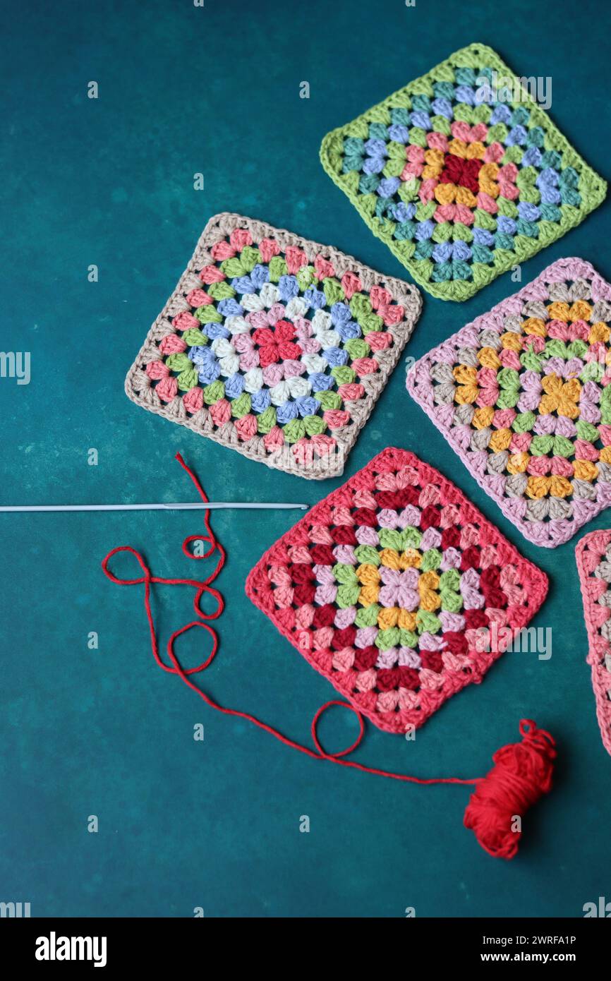 Projet de crochet en fabrication. Carrés au crochet colorés gros plan photo. Haut fabriqué à la main en cours de traitement. Banque D'Images