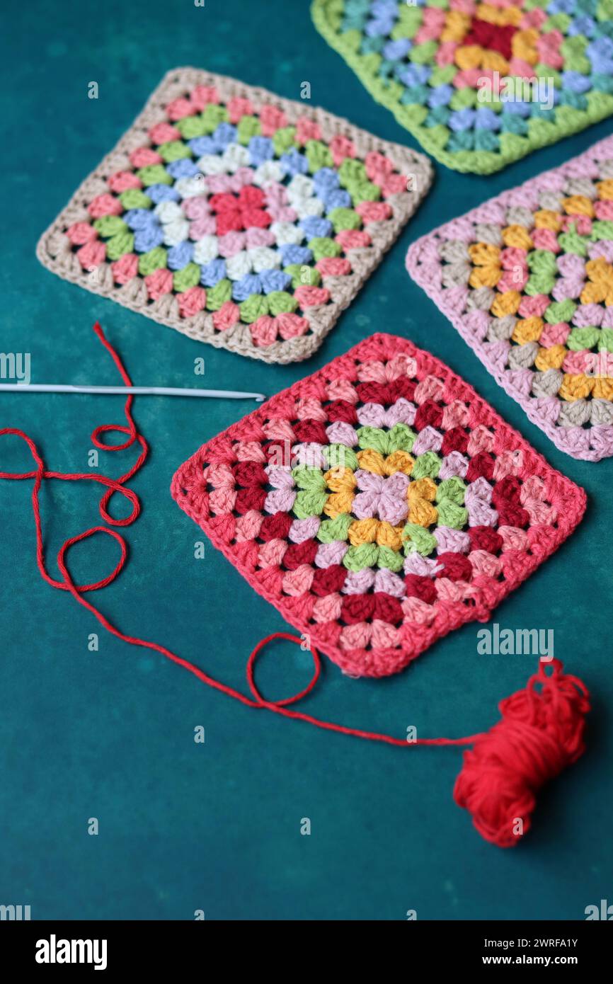 Projet de crochet en fabrication. Carrés au crochet colorés gros plan photo. Haut fabriqué à la main en cours de traitement. Banque D'Images