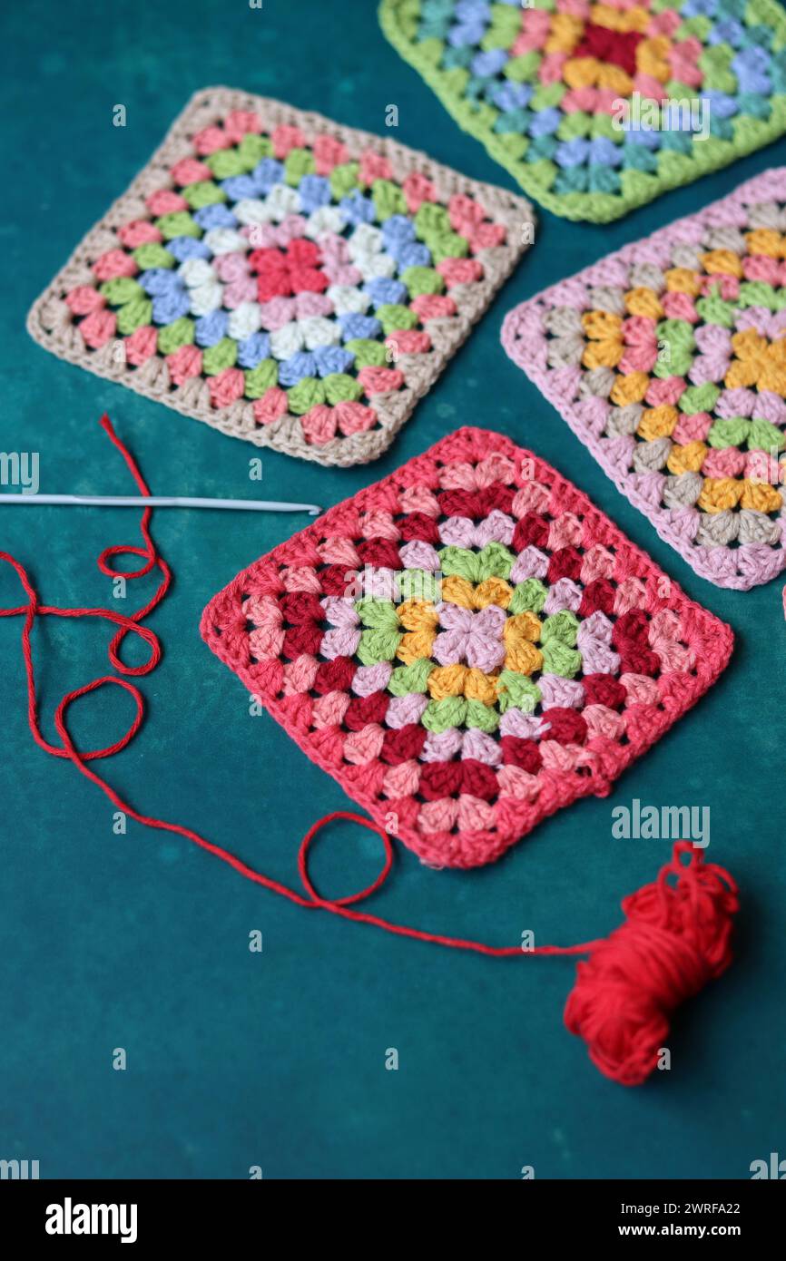 Projet de crochet en fabrication. Carrés au crochet colorés gros plan photo. Haut fabriqué à la main en cours de traitement. Banque D'Images