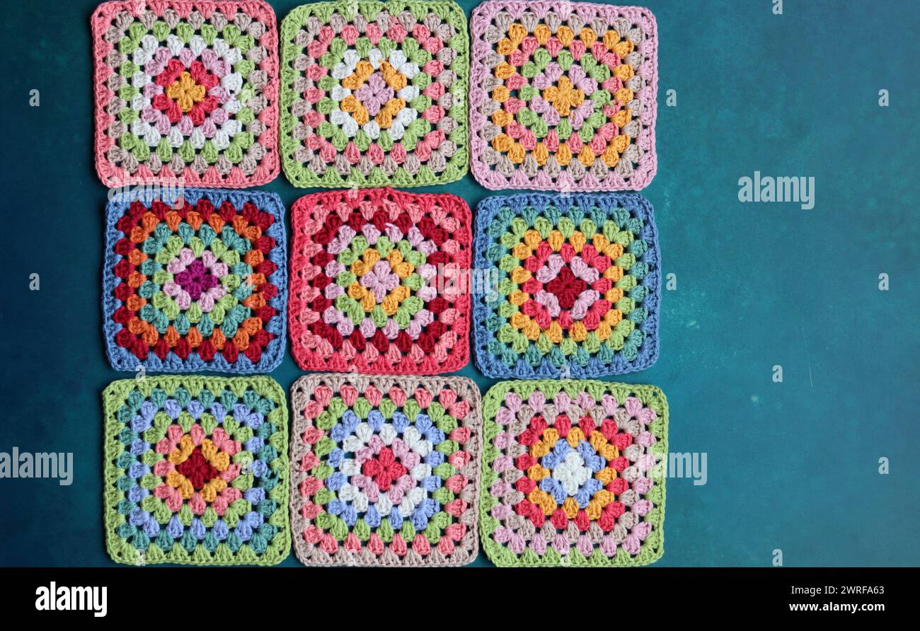 Projet de crochet en fabrication. Carrés au crochet colorés gros plan photo. Haut fabriqué à la main en cours de traitement. Banque D'Images