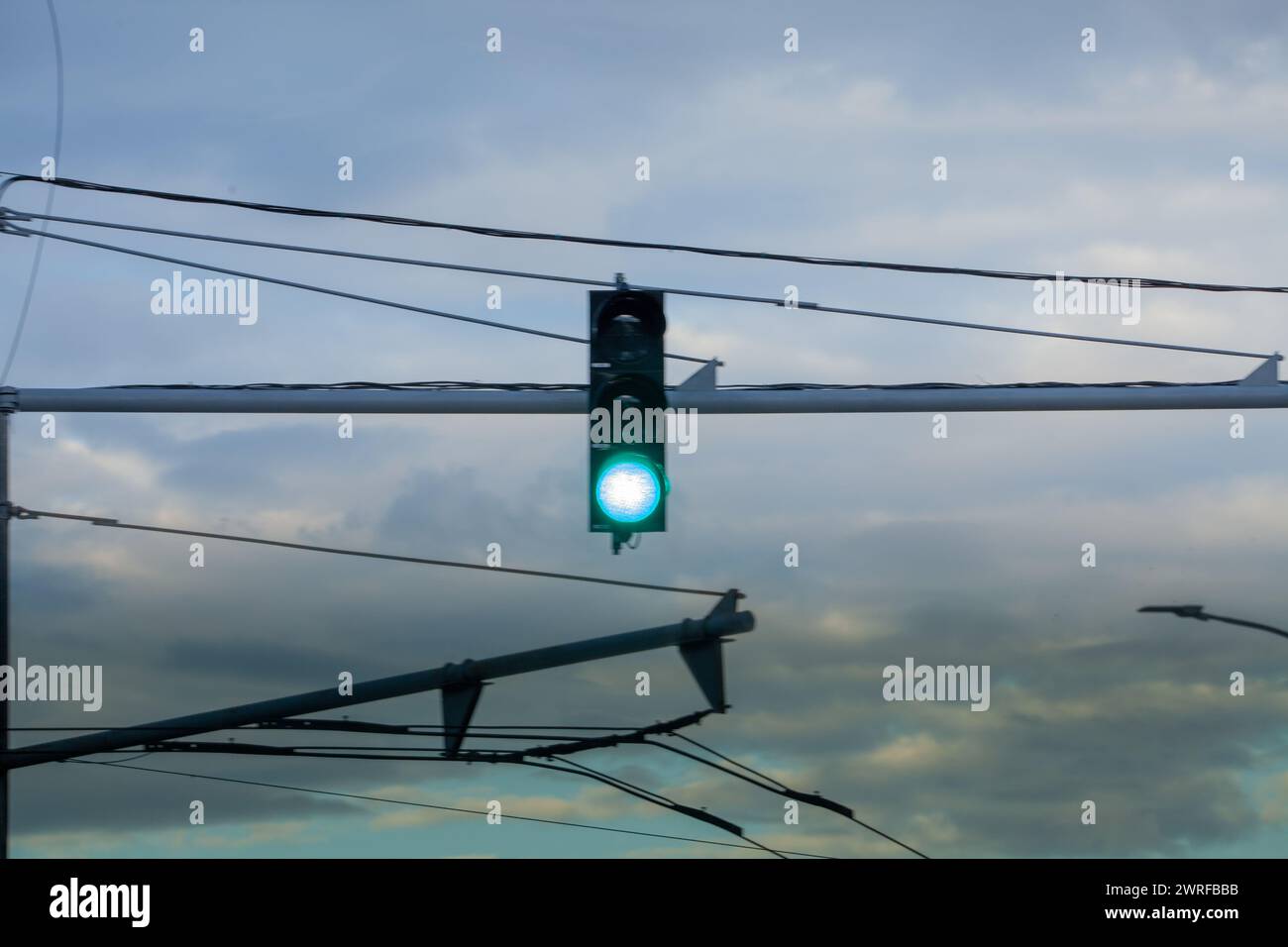 Feu de circulation vert brûlant sur le fond de nuages sombres. voyager à l'intérieur un jour de pluie. Banque D'Images