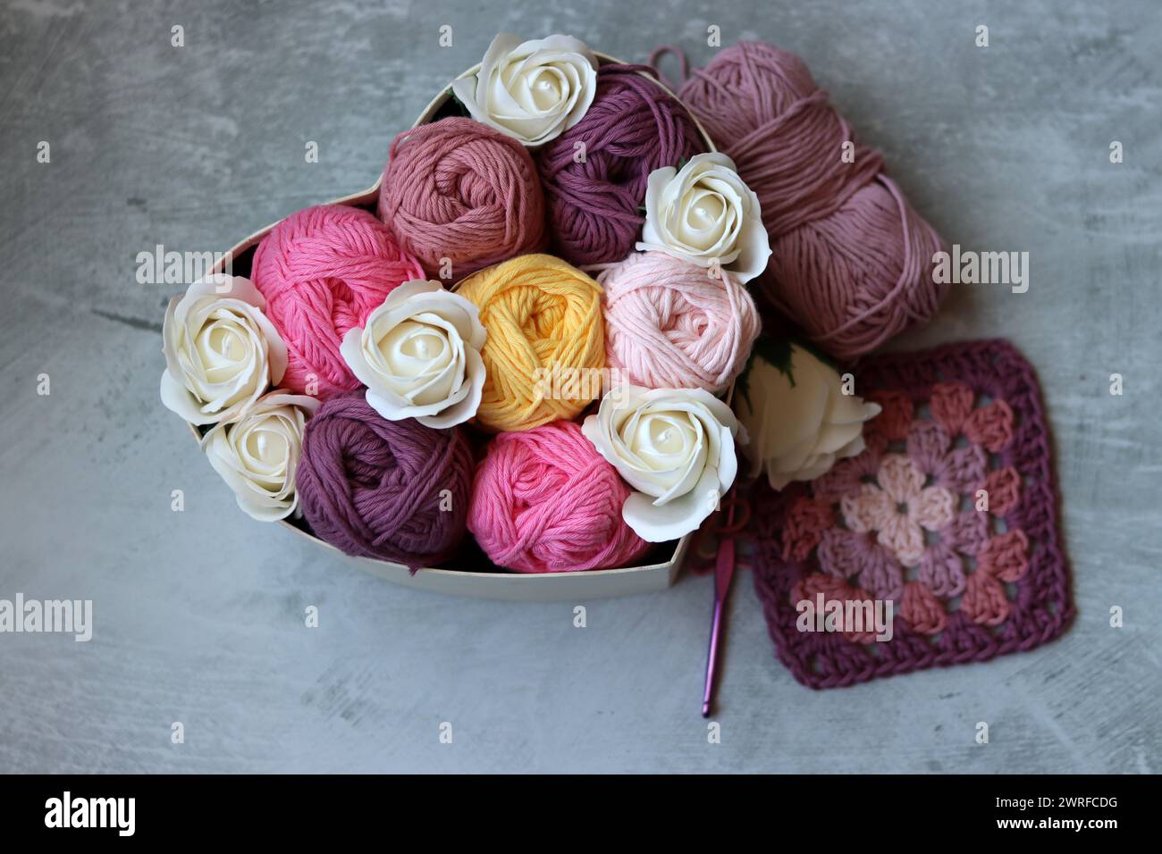 Boîte en forme de coeur avec des roses blanches et du fil de coton sur un fond gris. Texture de fil de coton gros plan photo. Concept d'art et d'artisanat. Banque D'Images