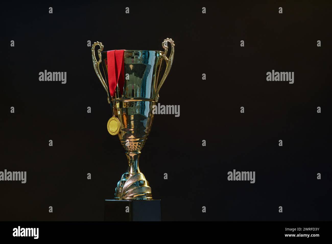 Image de fond minimale de la coupe de trophée et de la médaille d'or avec ruban rouge sur fond noir espace de copie Banque D'Images