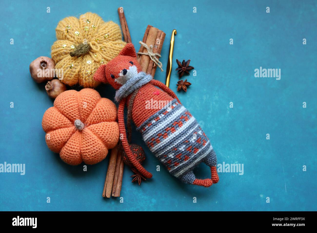 Renard jouet tricoté, boules de fil et décorations d'automne sur fond texturé avec espace pour le texte. Jouet amigurumi mignon. Banque D'Images