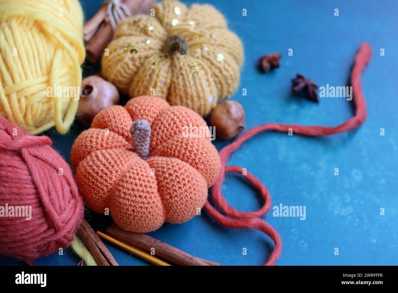 Tricoter des natures mortes d'automne. Aiguilles à tricoter, fils de laine, anis, cannelle, citrouille crochetée sur des idées cadeaux de jour de Thanksgiving gris clair. Banque D'Images
