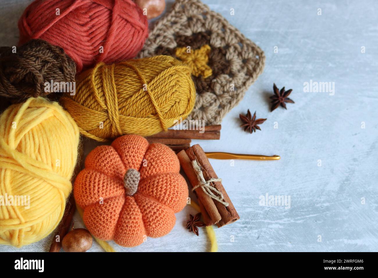 Jouets tricotés, boules de fil et décorations d'automne sur fond texturé avec espace pour le texte. Jouet amigurumi mignon. Banque D'Images