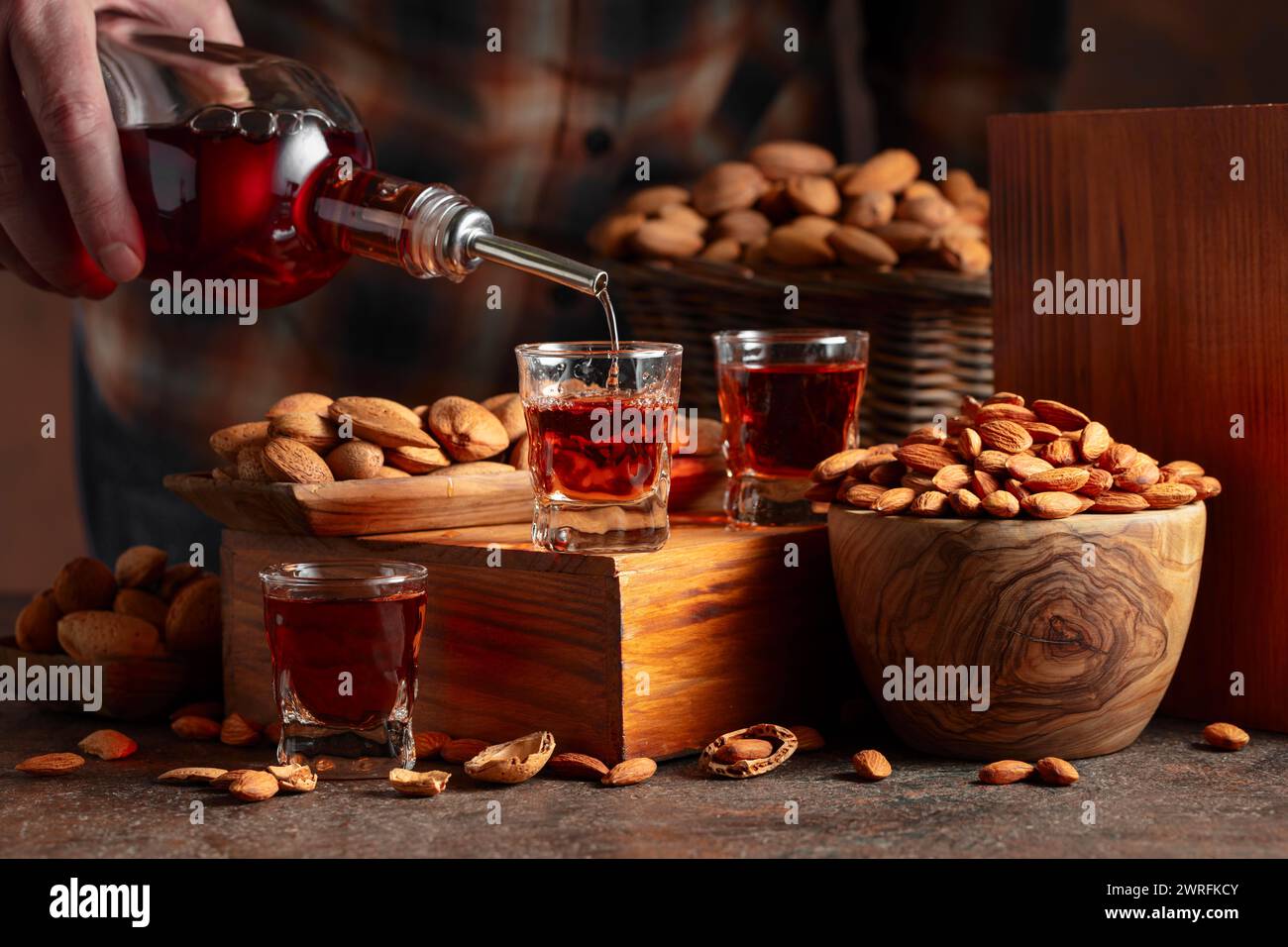 Liqueur italienne Amaretto avec des noix d'amandes sur une table vintage. La liqueur est versée d'une bouteille dans un verre. Banque D'Images