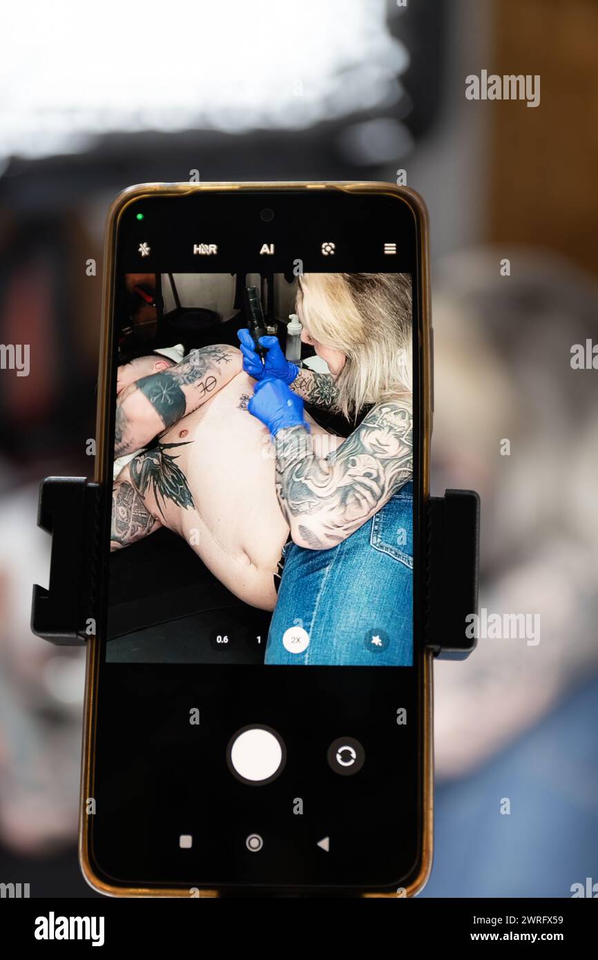 Photo verticale un gros plan de l'écran d'un smartphone montrant un tatoueur au travail, en se concentrant sur l'art et les compétences impliquées. Copier espace.concept busi Banque D'Images