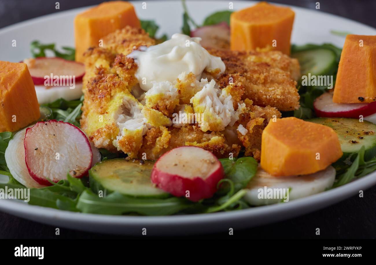 Filets de poisson enrobés de fromage et de chapelure avec une salade mélangée. Banque D'Images