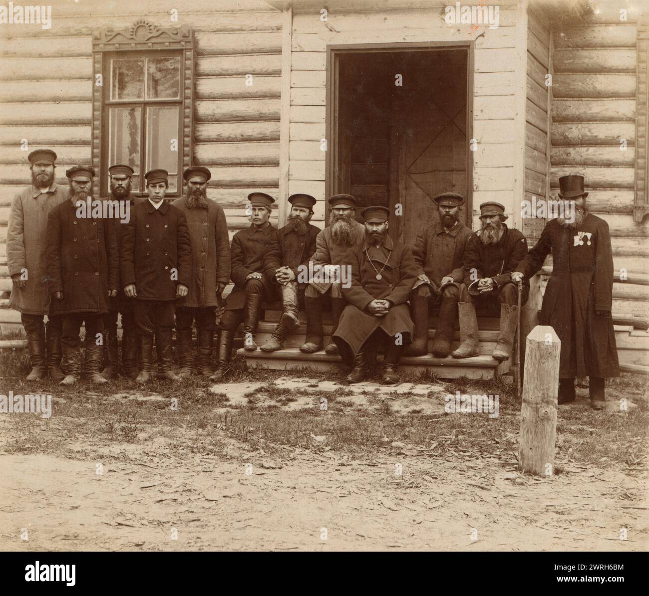 Groupe de paysans de Korobovo, 1910. Douze hommes posent devant un bâtiment en rondins. Dans album : vues le long de la haute Volga, de Kashin à Makarev, Empire russe. Banque D'Images