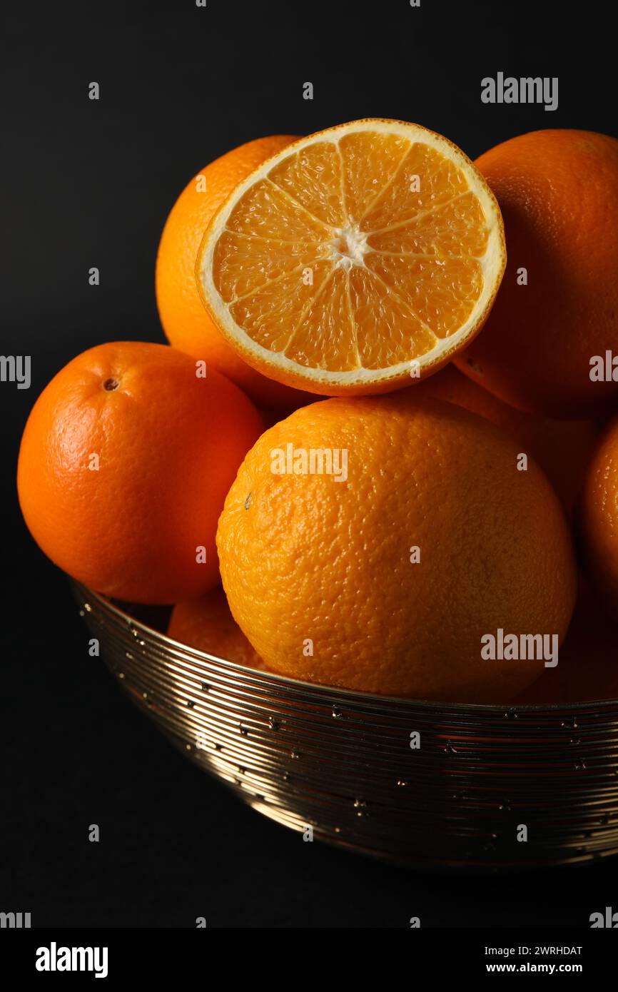 Bol avec des oranges juteuses mûres sur fond noir Banque D'Images