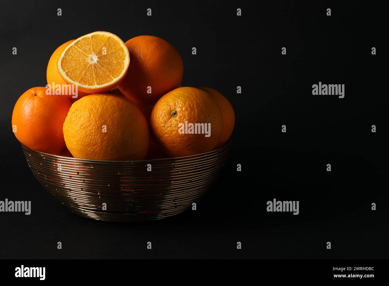 Bol avec des oranges juteuses mûres sur fond noir. Espace pour le texte Banque D'Images