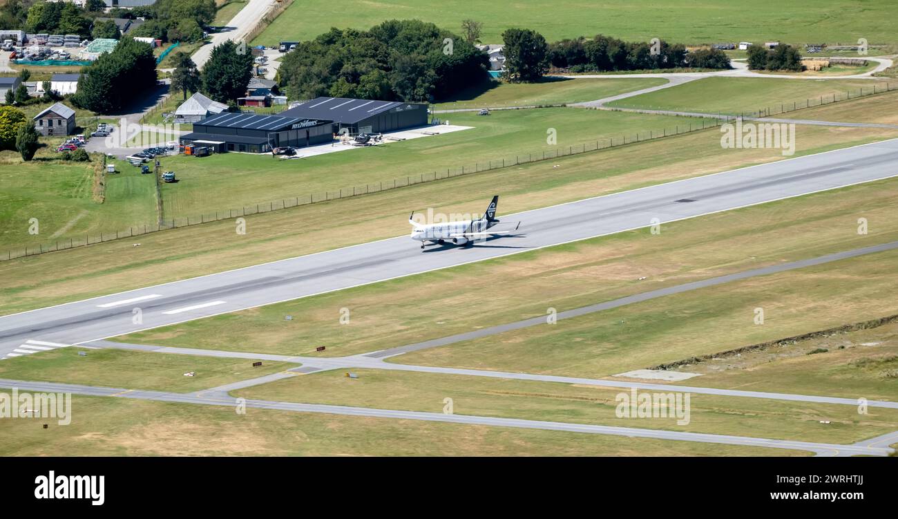 Queenstown, Nouvelle-Zélande - 30 décembre 2023. Un avion d'Air New Zealand commence son ascension depuis une piste au milieu d'un paysage de champs luxuriants. Banque D'Images