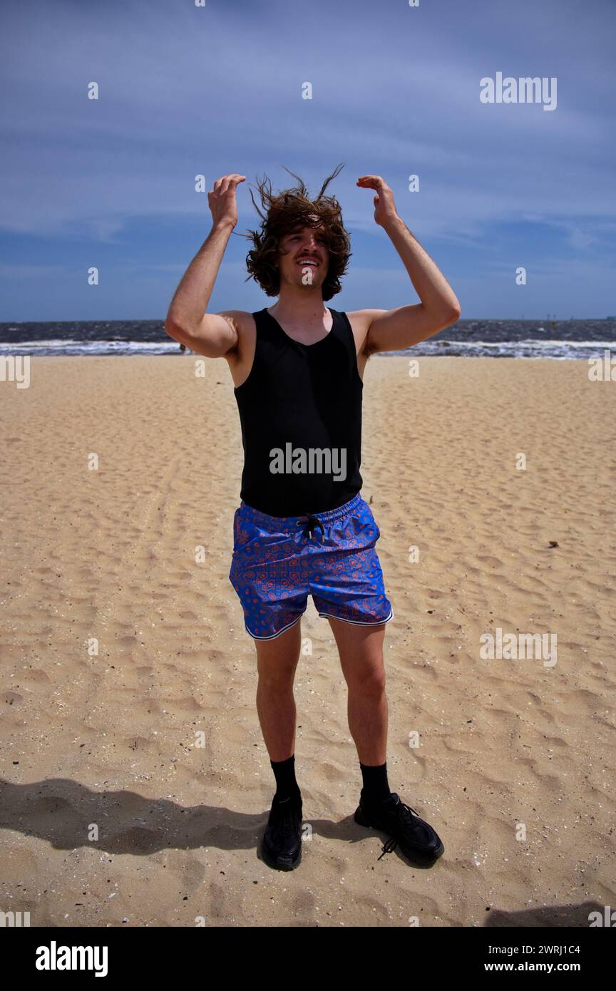 Jeune bel homme debout sur une plage de sable Banque D'Images