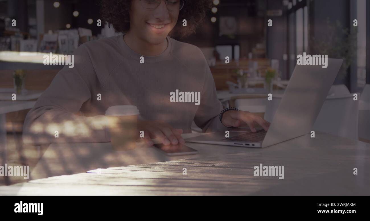 Image d'une femme souriante utilisant un ordinateur portable dans un café au-dessus des navetteurs accélérés marchant en ville Banque D'Images