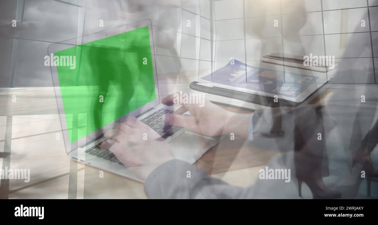 Image de mains utilisant un ordinateur portable avec un écran vert sur les navetteurs accélérés marchant dans un bâtiment moderne Banque D'Images