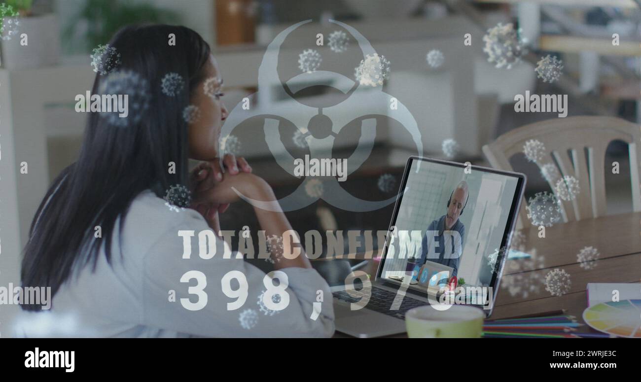 Jeune femme biraciale regarde un écran d'ordinateur portable avec des graphiques de virus Banque D'Images