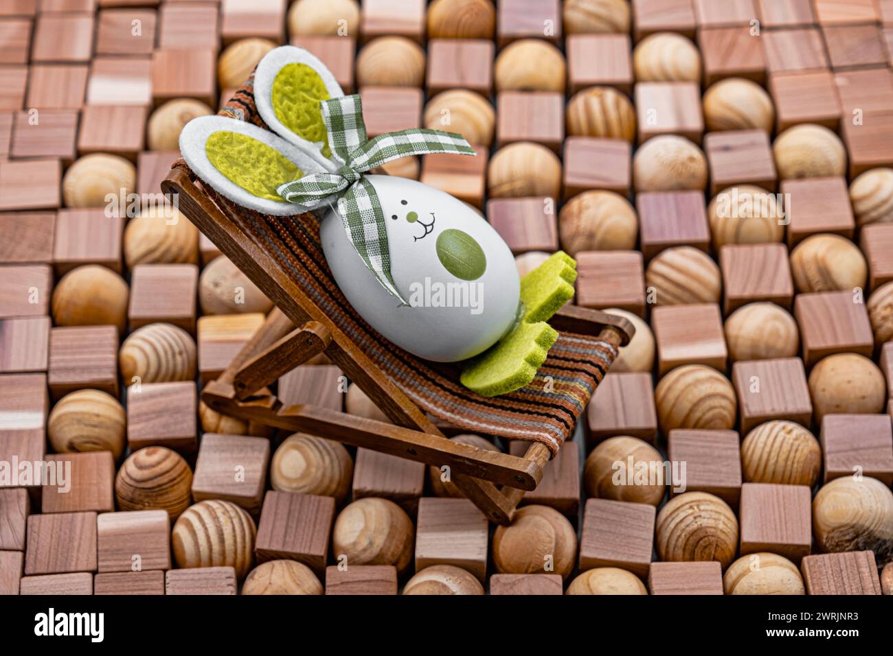 un jouet en peluche dans une chaise longue vintage sur un fond fait de cubes et de boules de mosaïques en bois Banque D'Images