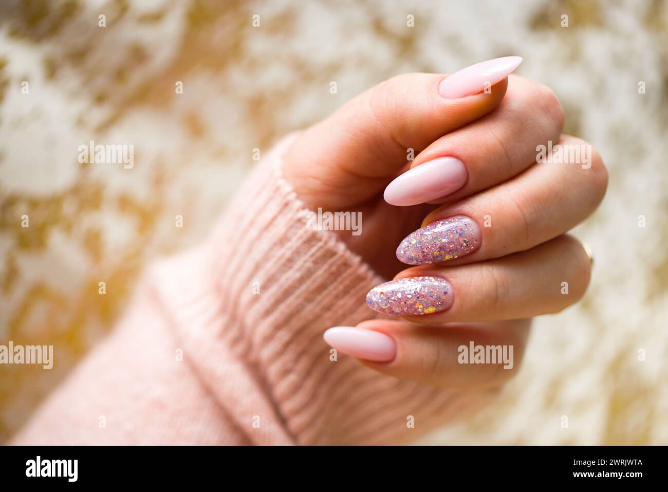 Une image représentant une main de femme avec de superbes ongles en gel rose, méticuleusement peints et ornés de paillettes multicolores élégantes. La main est bien-M. Banque D'Images