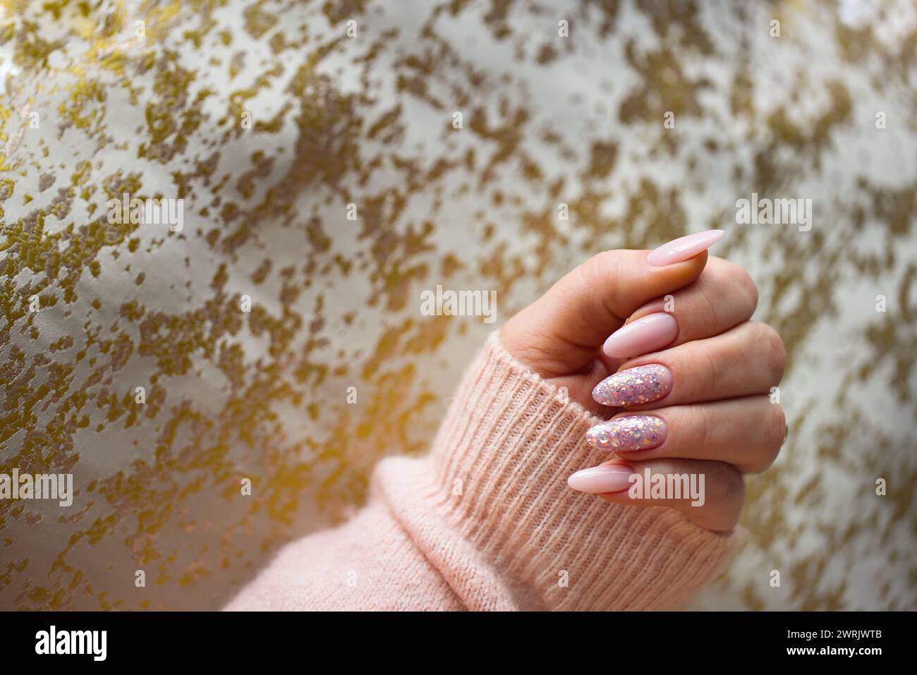 Une image représentant une main de femme avec de superbes ongles en gel rose, méticuleusement peints et ornés de paillettes multicolores élégantes. La main est bien-M. Banque D'Images