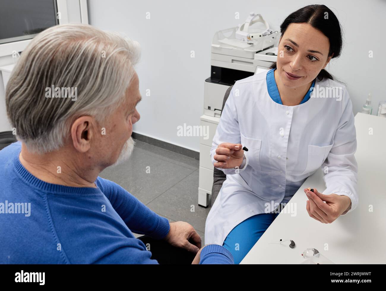 Audiologiste féminine consultant pour un patient âgé aux cheveux gris souffrant de troubles auditifs au centre d'audition. Consultation du médecin auditif Banque D'Images