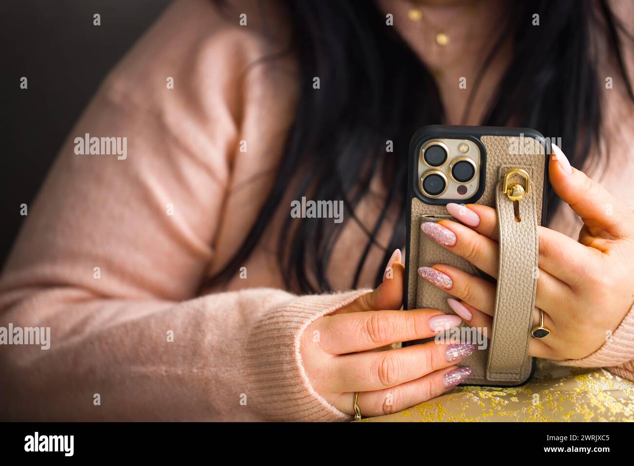 Gros plan des mains d'une femme tenant un smartphone. La femme a de superbes ongles en gel rose, méticuleusement peints avec deux ongles ornés de stylets Banque D'Images