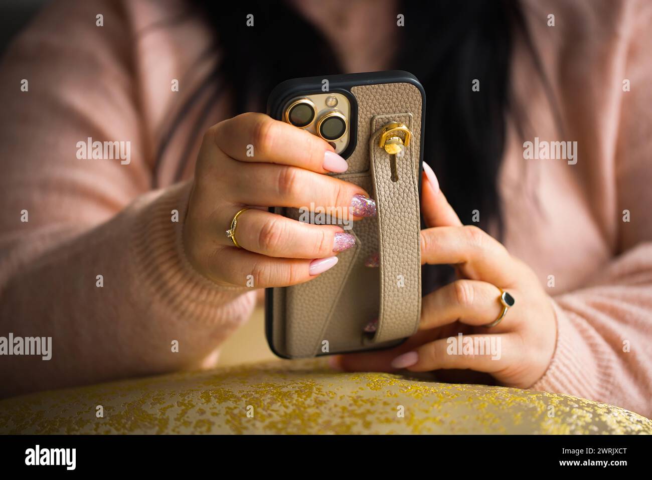 Gros plan des mains d'une femme tenant un smartphone. La femme a de superbes ongles en gel rose, méticuleusement peints avec deux ongles ornés de stylets Banque D'Images