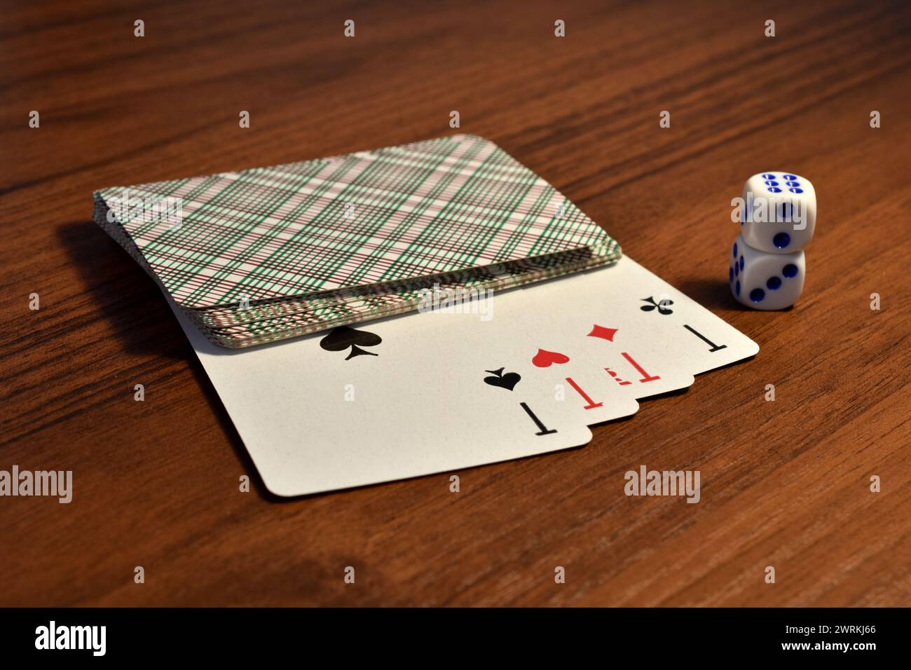 Quatre as d'un jeu de cartes, face visible, et des dés sont sur la table. Banque D'Images