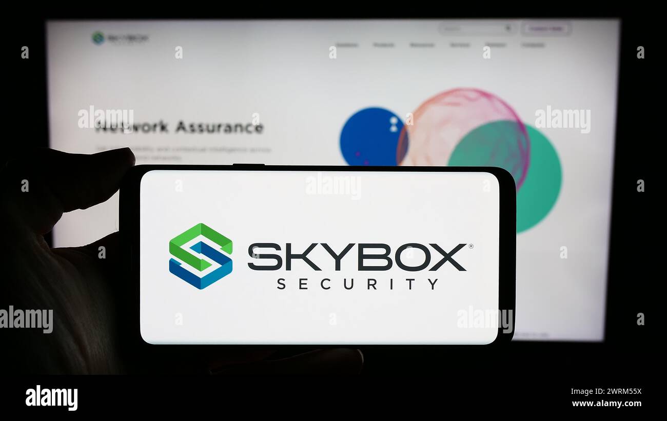 Personne tenant un téléphone portable avec le logo de la société américaine de cybersécurité Skybox Security Inc en face de la page Web de l'entreprise. Concentrez-vous sur l'affichage du téléphone. Banque D'Images