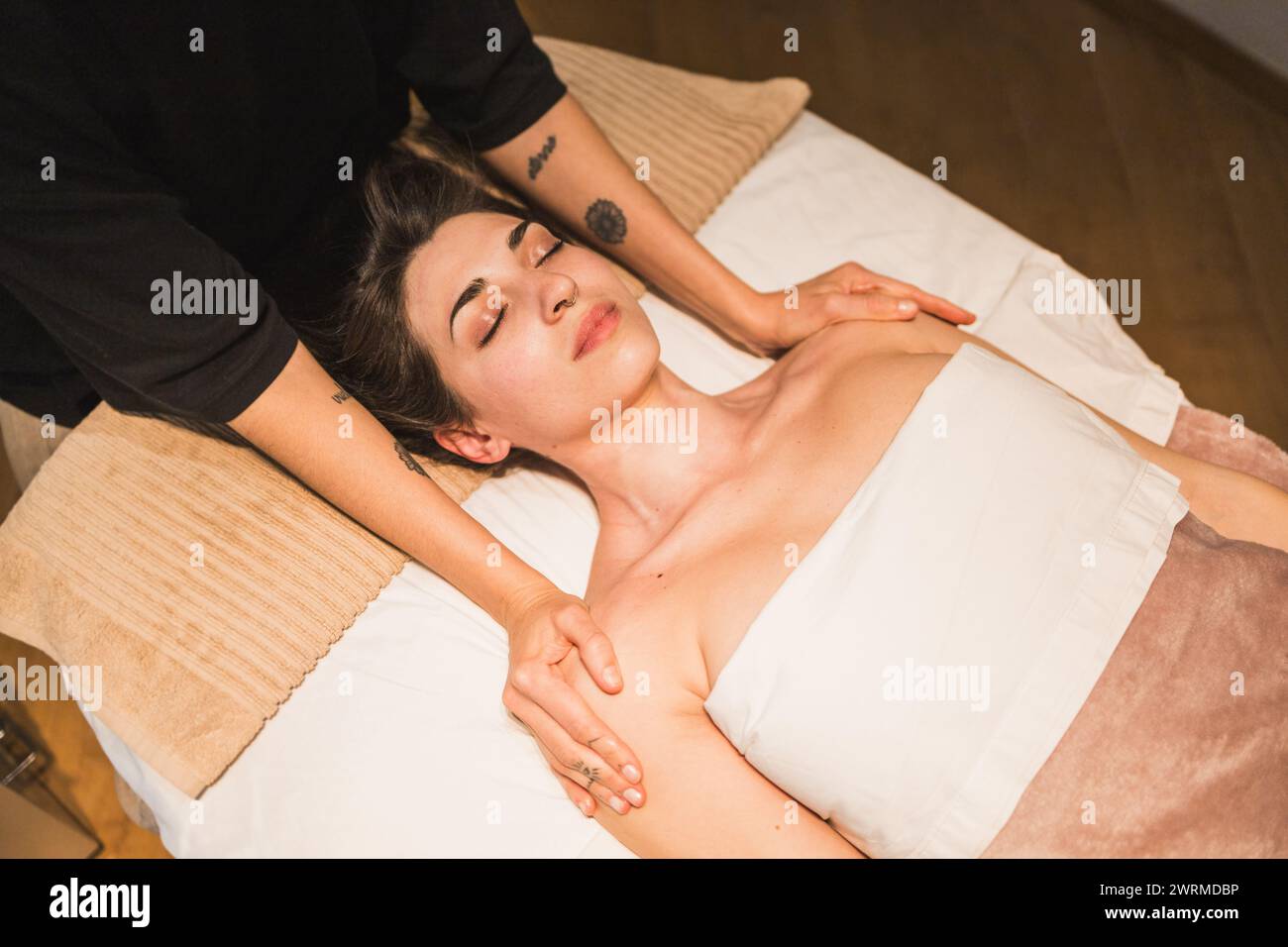 Femme bénéficie d'un massage relaxant des épaules dans un spa de bien-être avec un accent sur le confort et la tranquillité Banque D'Images