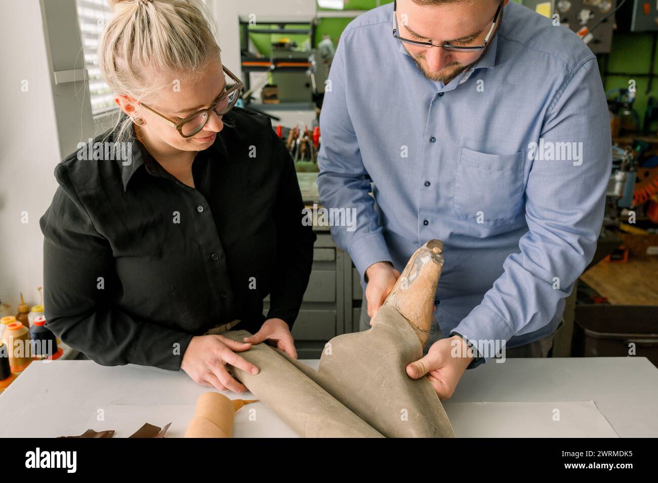 Deux artisans examinent une forme de chaussure au cours du processus méticuleux de fabrication de chaussures à la main dans un atelier de cordonnier lumineux et organisé en Autriche. Banque D'Images