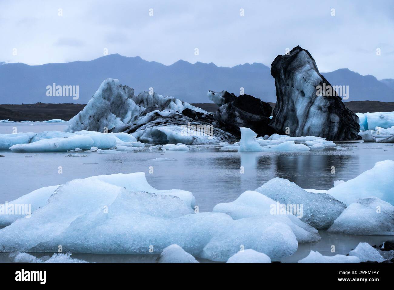 Un paysage évocateur de formations de glace saisissantes au milieu des eaux glaciaires de la lagune au parc national de Vatnajokull, sous la lumière tamisée d'une Islande Banque D'Images