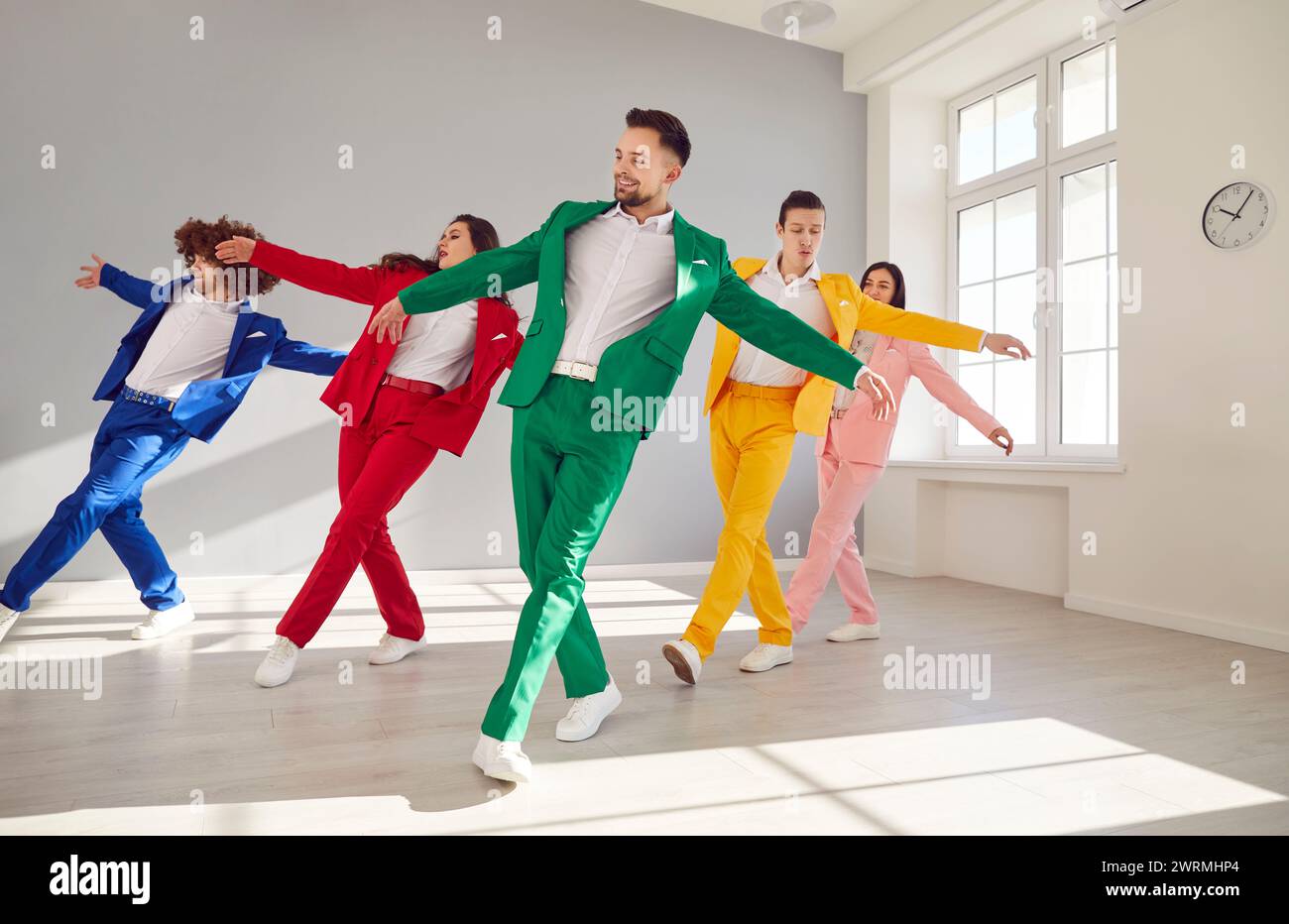 Groupe de personnes élégantes dans les costumes d'affaires colorés dansant joyeusement. Hommes et femmes dans des costumes d'affaires colorés dansent gracieusement dans des tenues vibrantes Banque D'Images