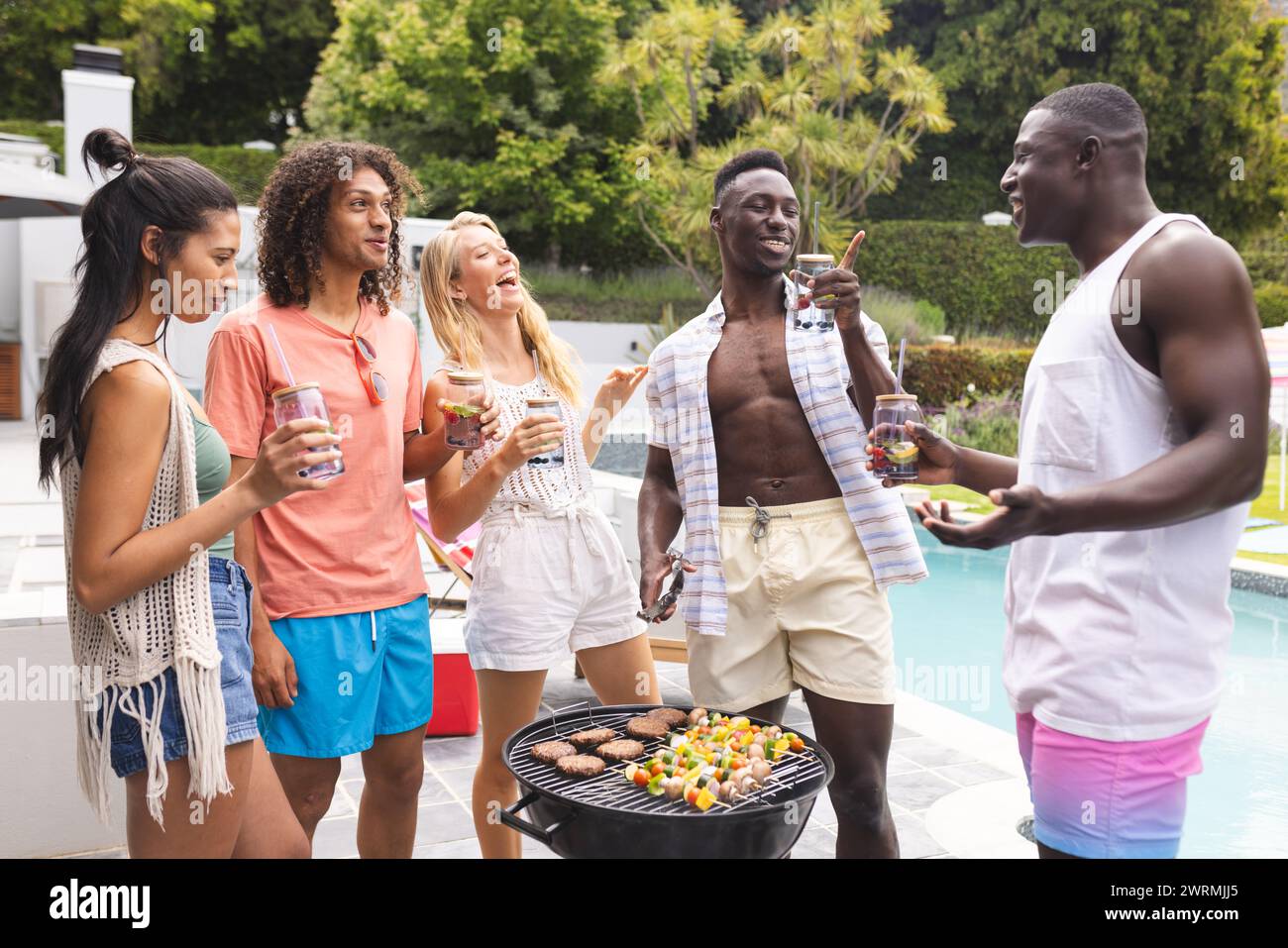 Groupe diversifié d'amis profitant d'un barbecue au bord de la piscine Banque D'Images