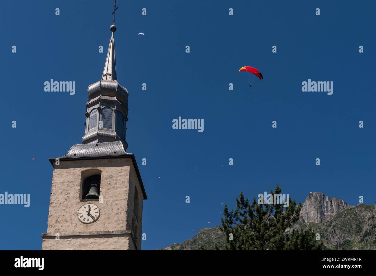 Parapente survolant le clocher de l'église Saint Michel avec le pic du Brévent en arrière-plan en été, Chamonix, haute Savoie, France Banque D'Images