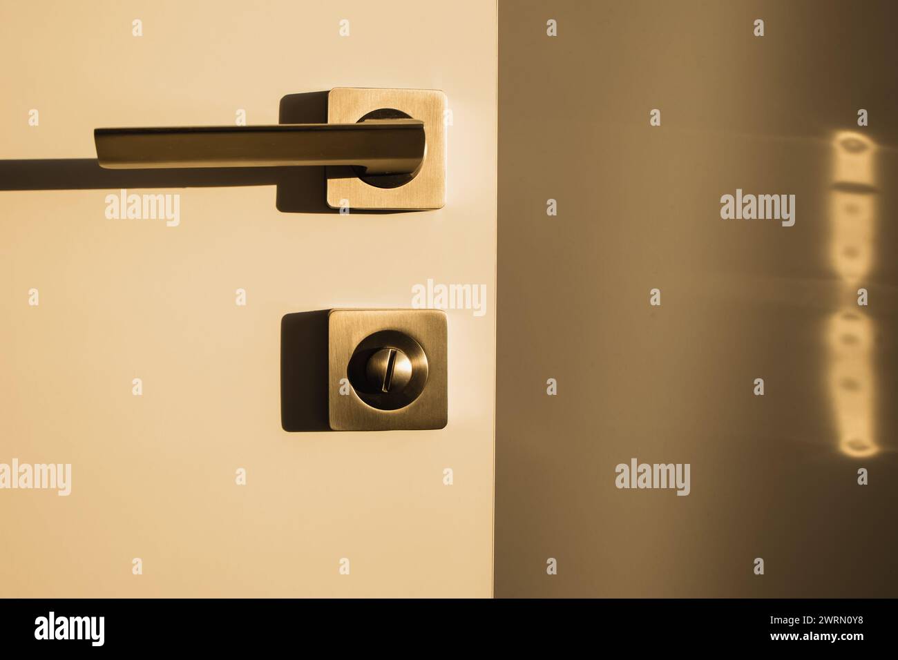 Porte avec poignée métallique en lumière chaude, design intérieur moderne Banque D'Images