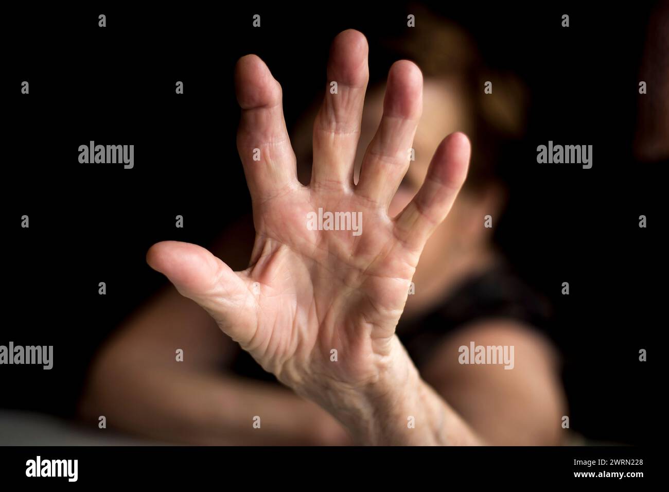 La vieille femme couvre l'appareil photo d'une main ridée. Banque D'Images