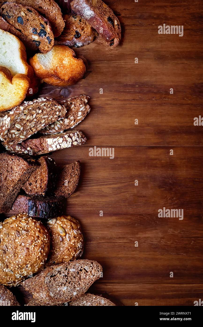 Assortiment de pain cuit au four sur le fond d'une table en bois. graines de blé dans un tamis et graines de sarrasin, épillets de blé et aussi avoine et pru Banque D'Images