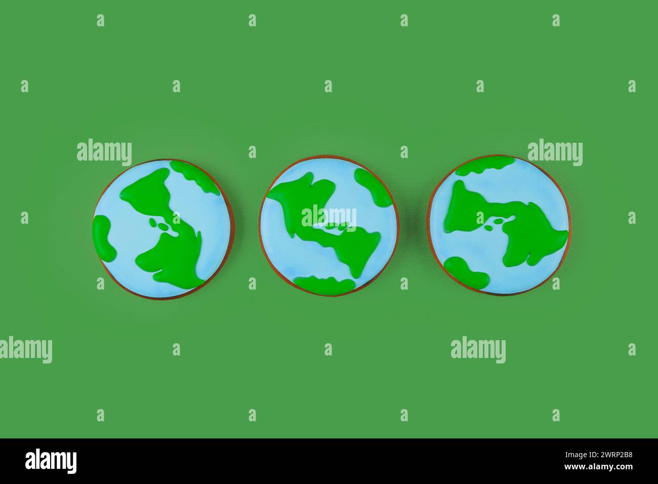 Concept de jour de la Terre. Trois biscuits en forme de Terre sur fond vert. Banque D'Images