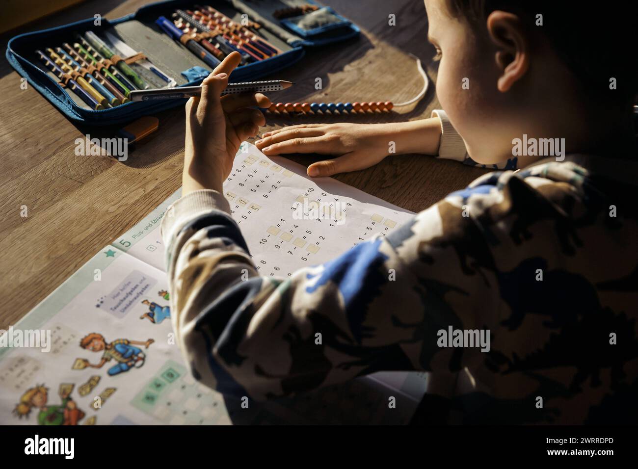 Ein sechsjaehriger Junge macht zu Hause Mathematik-Hausaufgaben der ersten Klasse in einem Arbeitsheft. Berlin, 13.03.2024. Berlin Deutschland *** A s Banque D'Images