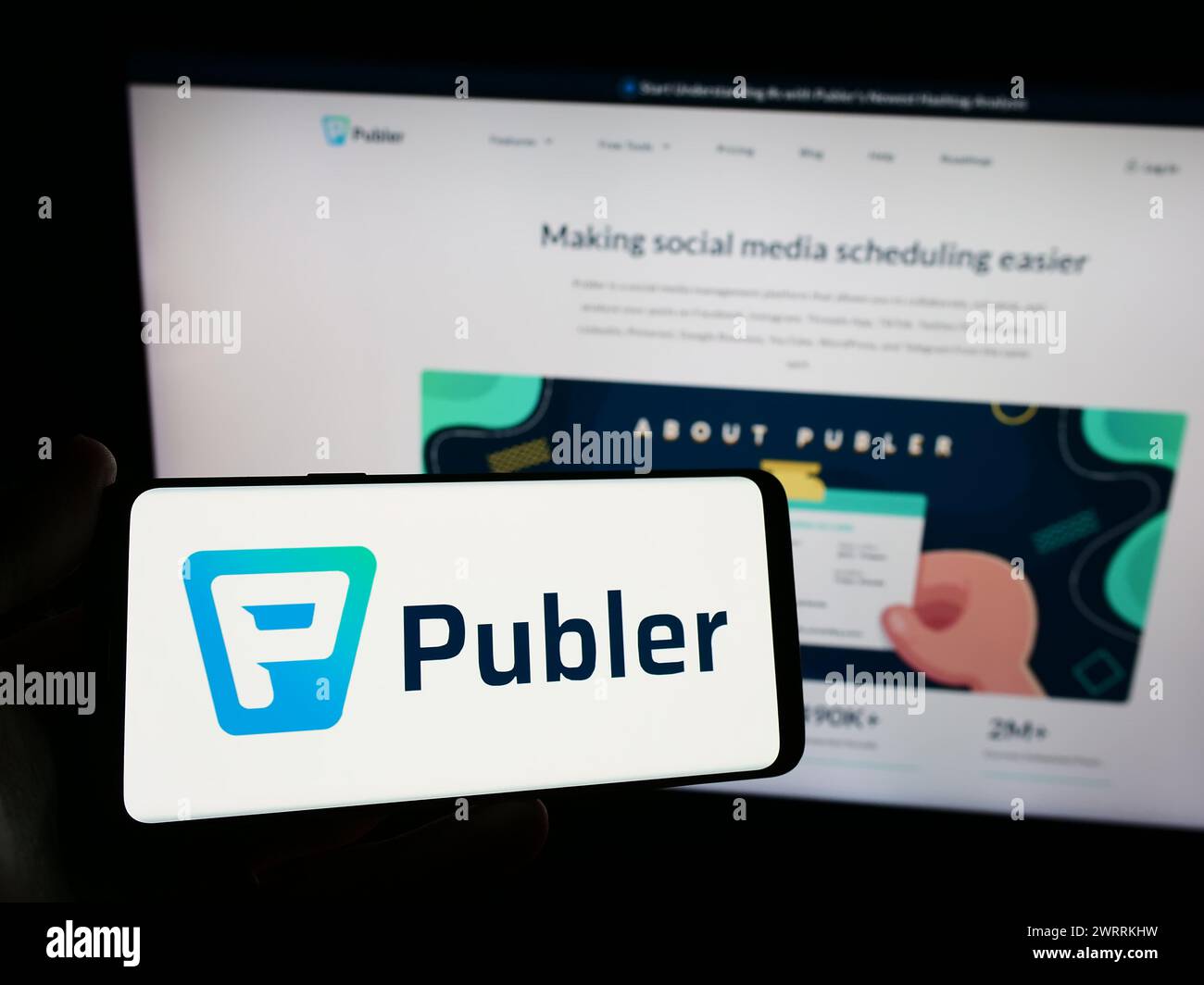 Personne tenant un smartphone avec le logo de la société de gestion des médias sociaux Kalemi Code LLC (Publer) en face du site Web. Concentrez-vous sur l'affichage du téléphone. Banque D'Images