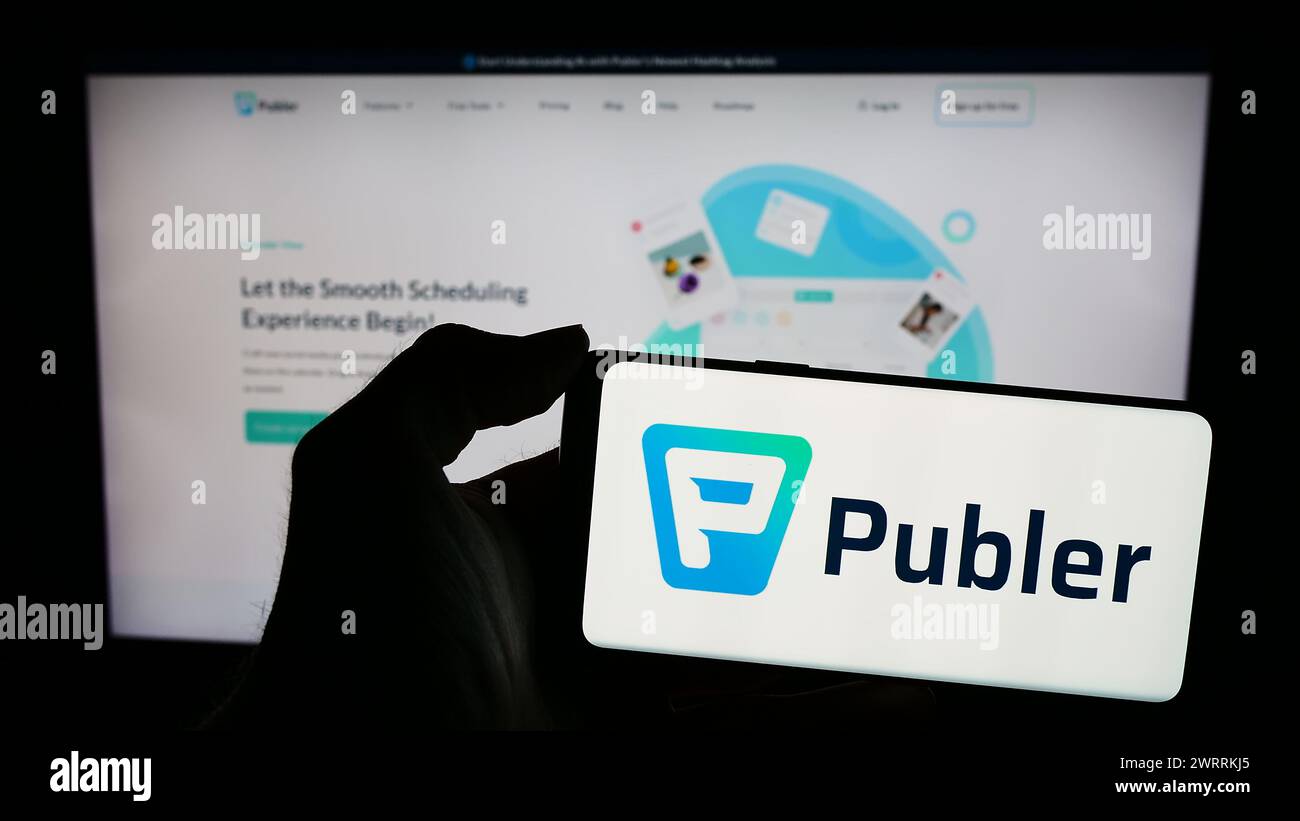 Personne tenant le téléphone portable avec le logo de la société de gestion des médias sociaux Kalemi Code LLC (Publer) devant la page Web. Concentrez-vous sur l'affichage du téléphone. Banque D'Images