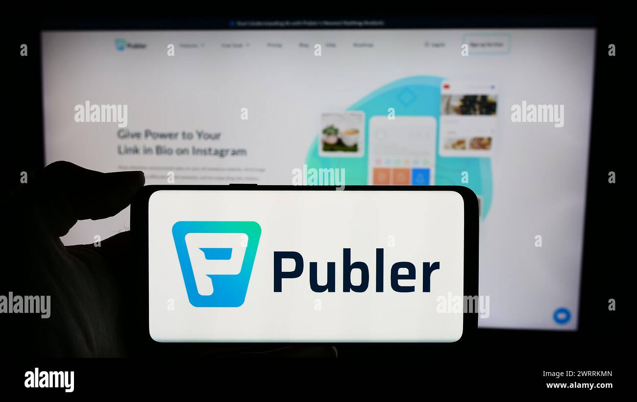 Personne tenant un téléphone portable avec le logo de la société de gestion des médias sociaux Kalemi Code LLC (Publer) en face de la page Web. Concentrez-vous sur l'affichage du téléphone. Banque D'Images