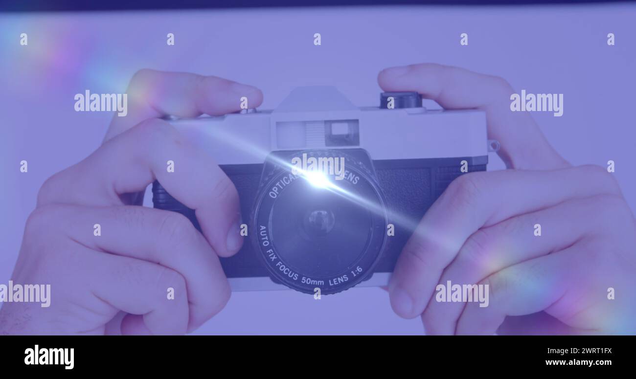 Spot de lumière contre gros plan de la main tenant un appareil photo numérique Banque D'Images